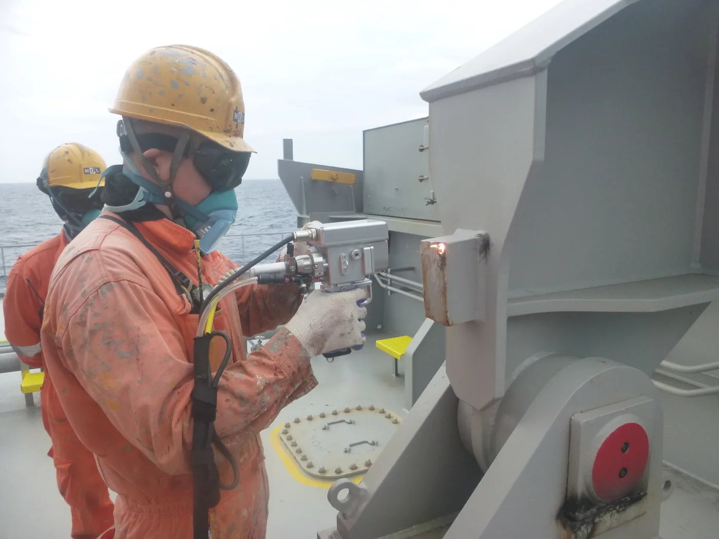 航海中の甲板で保護具を着用してレーザ施工を行う作業者